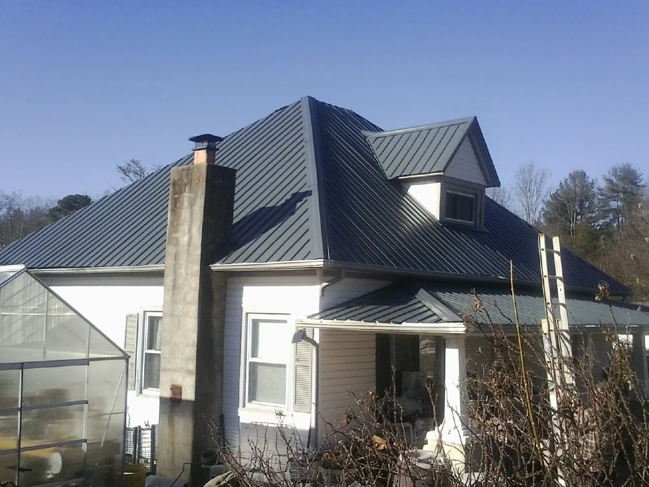 Dark blue standing seam metal roof on a white farmhouse with dormer — Slate & Tile Roof Repair by Roofing Brothers in Spring Run