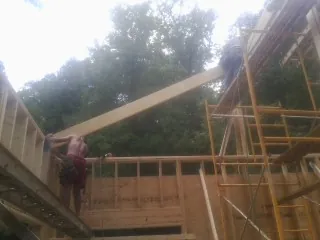 Carpenter raising a rafter beam on a new second story frame in Spring Run