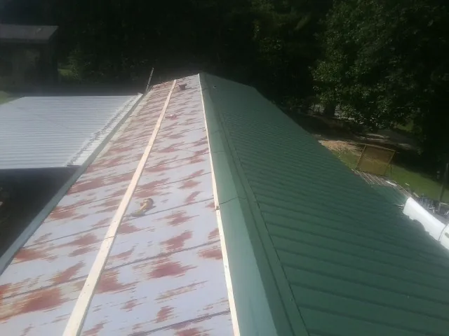 Old rusted panels beside newly installed green metal roofing — Wind Damage Roof Repair by Roofing Brothers in Spring Run
