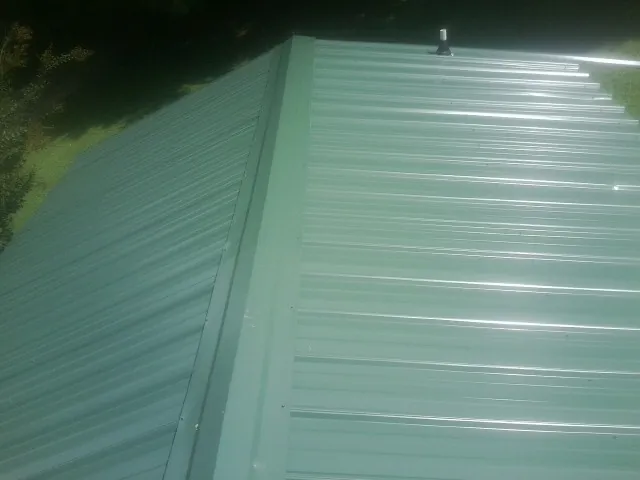 New green metal panels meeting at the ridge of a roof — Flat Roof Repair work by our crew in Spring Run