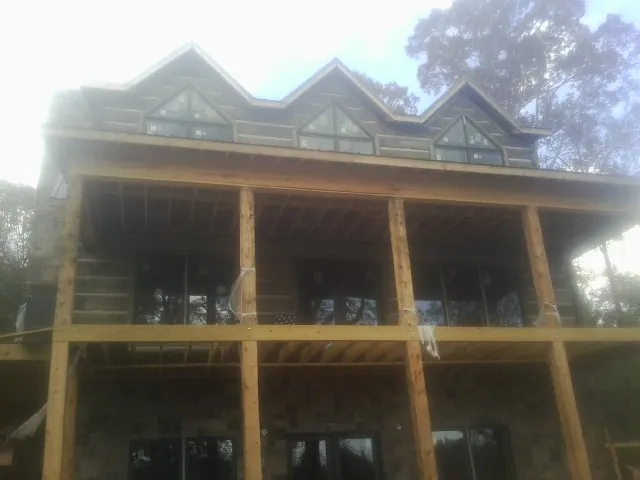 Dormers and porch framing on a large log home under construction — Roof Coating work by our crew in Spring Run