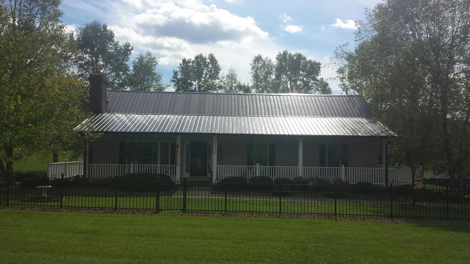 Gray metal roof on a brick ranch with a full width front porch — Gutter Guard Installation work by our crew in Spring Run