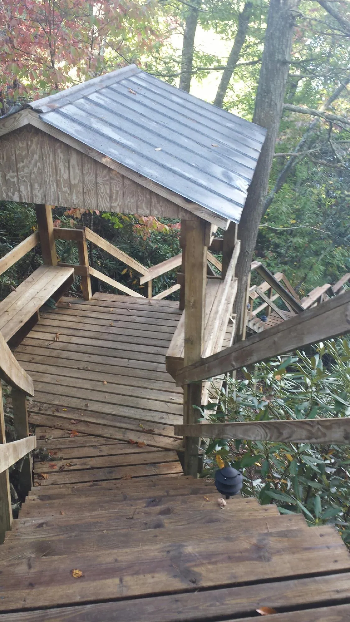 Metal roofed shelter over wooden steps on a wooded walkway — Skylight Repair & Installation work by our crew in Spring Run