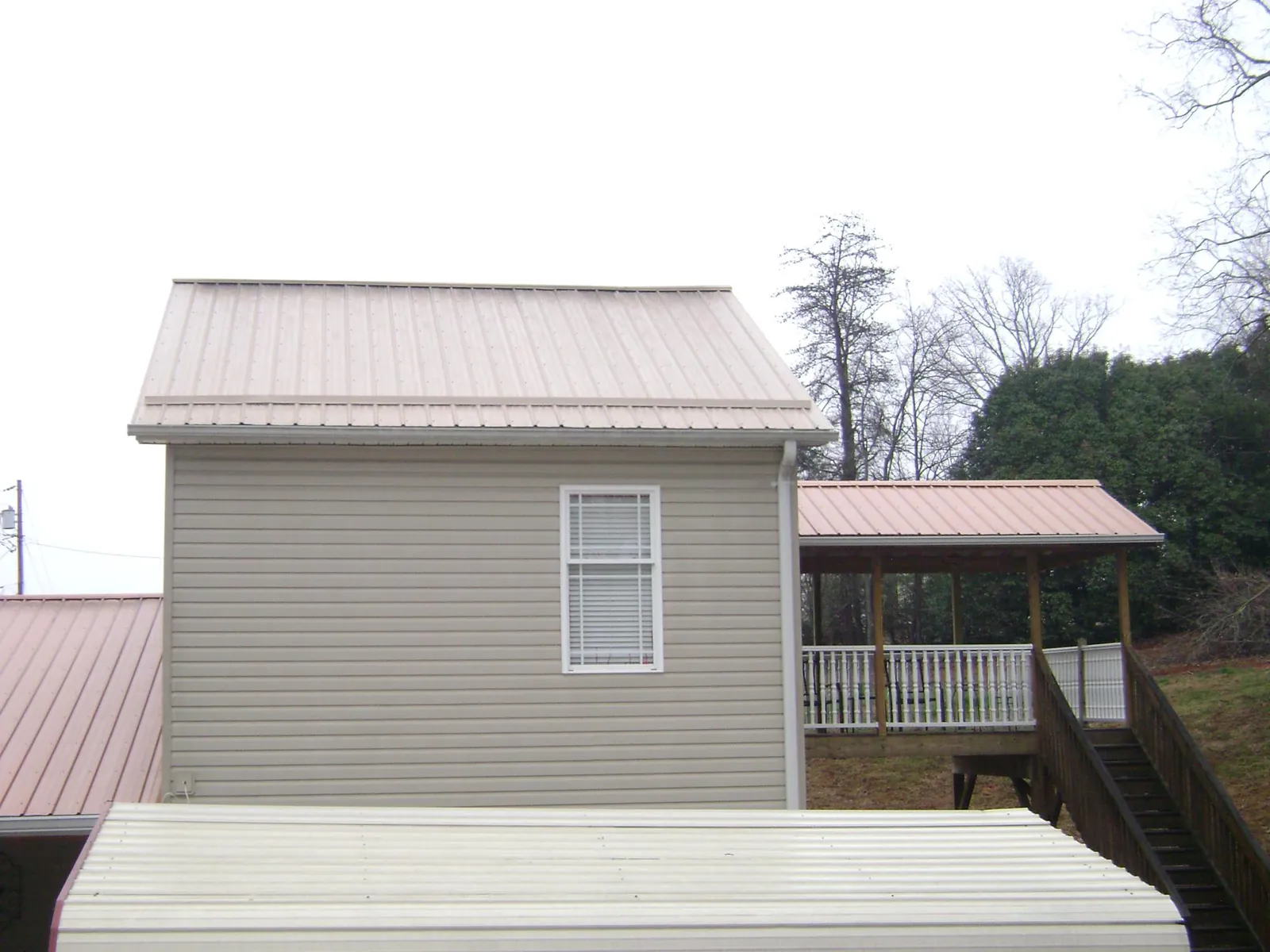 Tan metal roofs on a two story addition and attached porch, from a Roof Replacement job in Spring Run