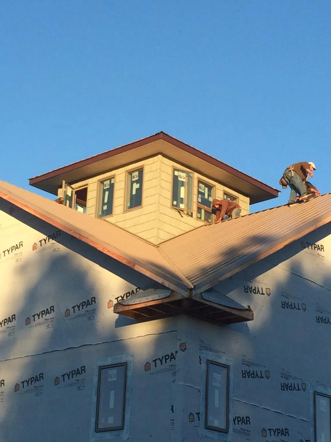 Roofers working around a rooftop cupola on a new metal roof at sunset — Roof Waterproofing in Spring Run by Roofing Brothers